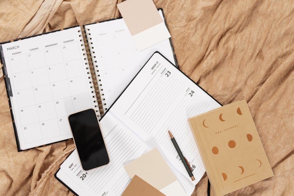 Open planners, smartphone and journal arranged on a neutral fabric background