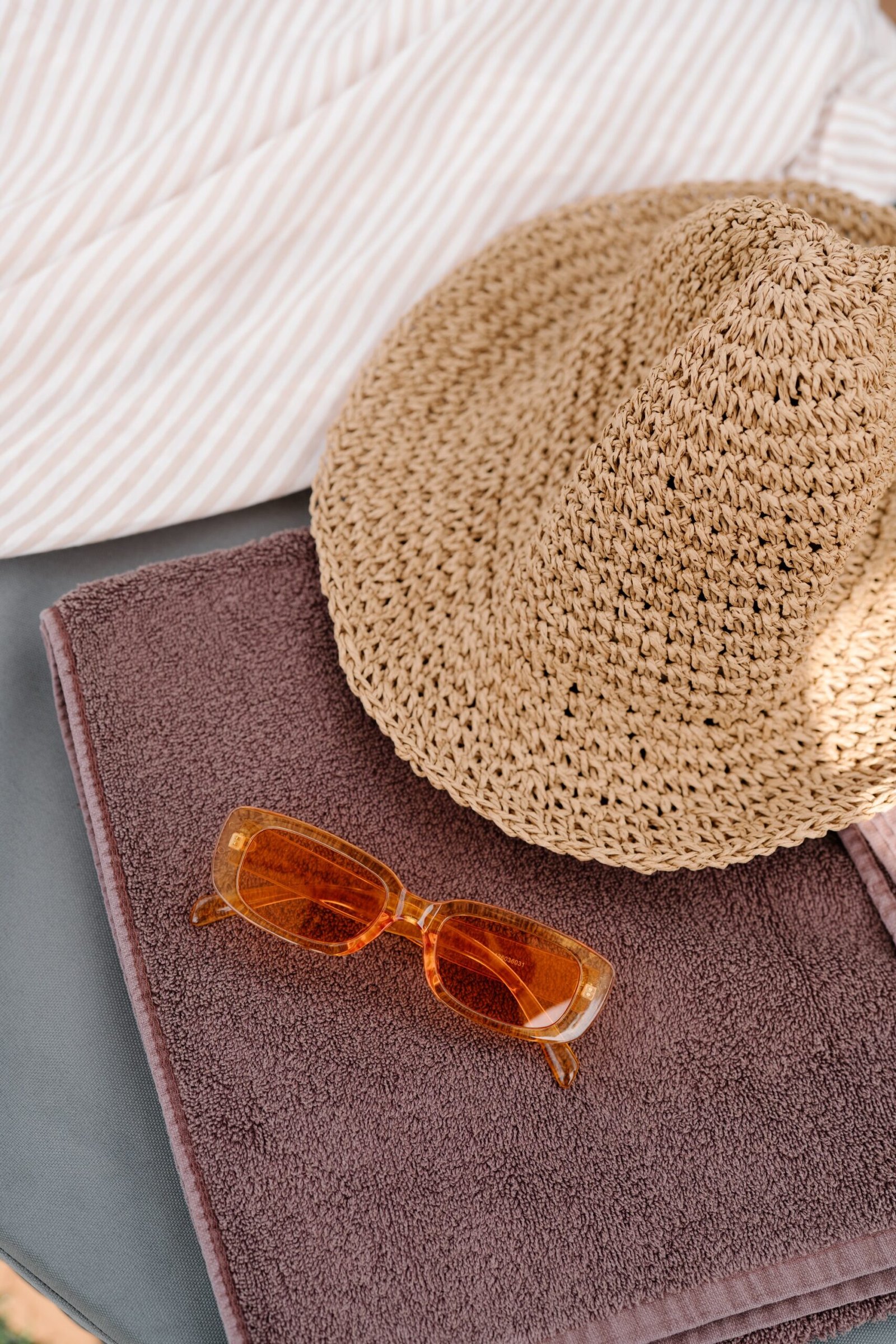 Woven sun hat and sunglasses resting on a folded towel
